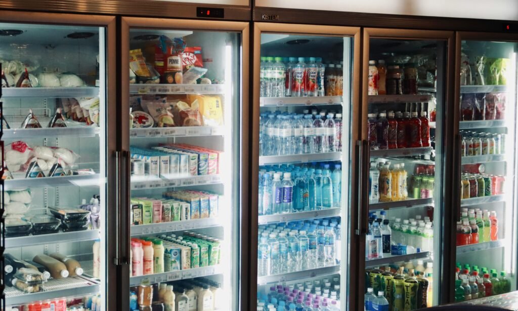 Panduan Lengkap Memilih Freezer yang Tepat untuk Menyimpan Makanan Lebih Lama Refrigerator display with various beverages and snacks in a store environment.